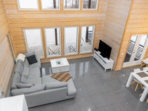 Un interior moderno con un sofá gris, una mesa de centro y un televisor sobre un mueble blanco.