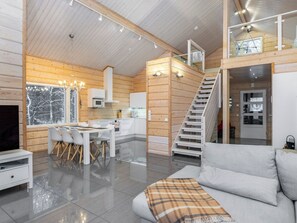Un interior moderno con comedor, cocina, escalera y sala de estar con sofá.