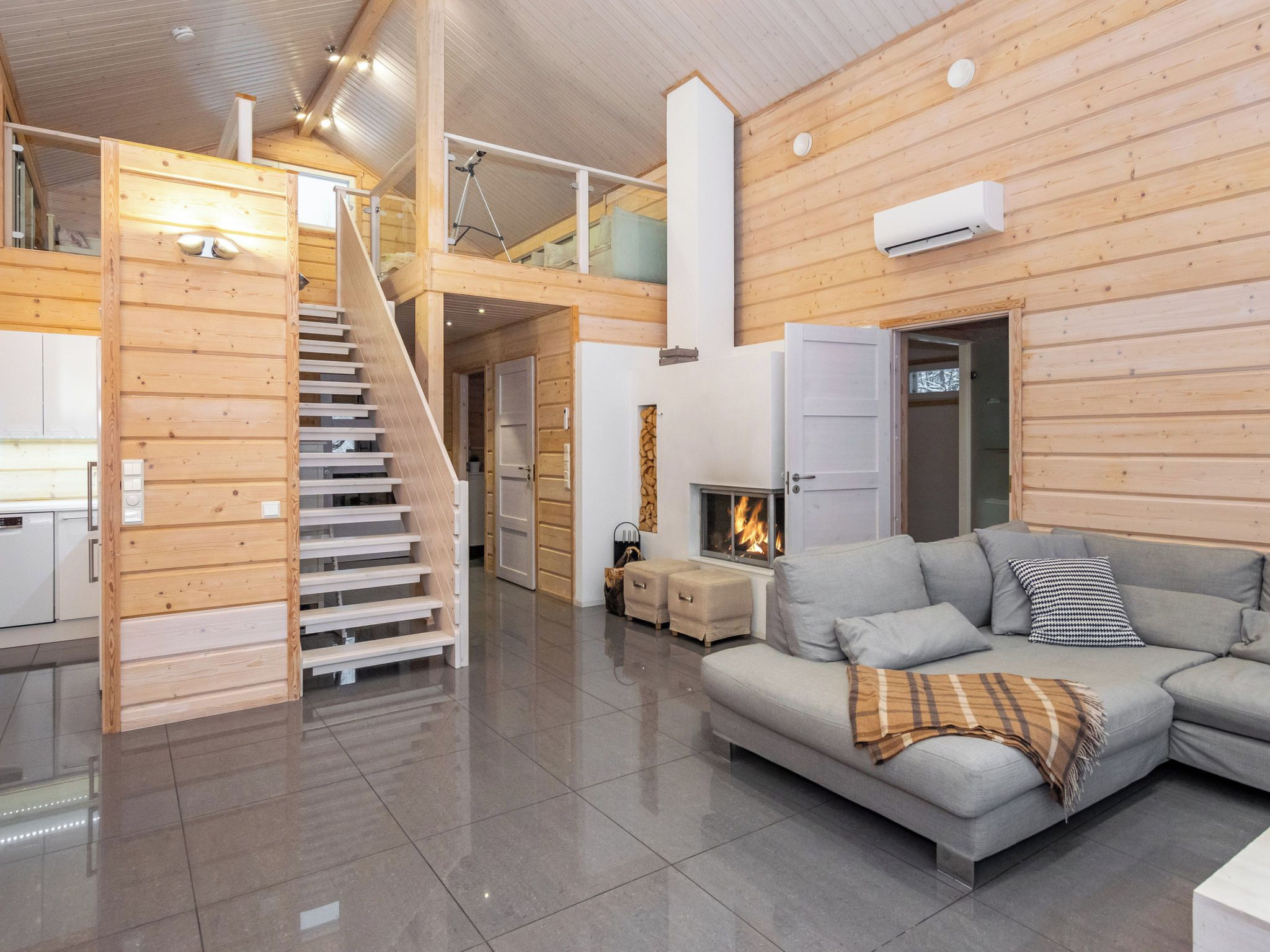 A spacious living area with a staircase, a fireplace, and a modern sofa.