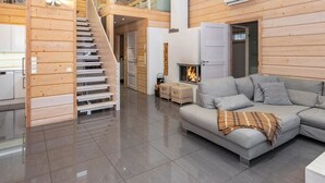 Un vaste espace de vie comprenant un escalier, une cheminée et un canapé moderne.