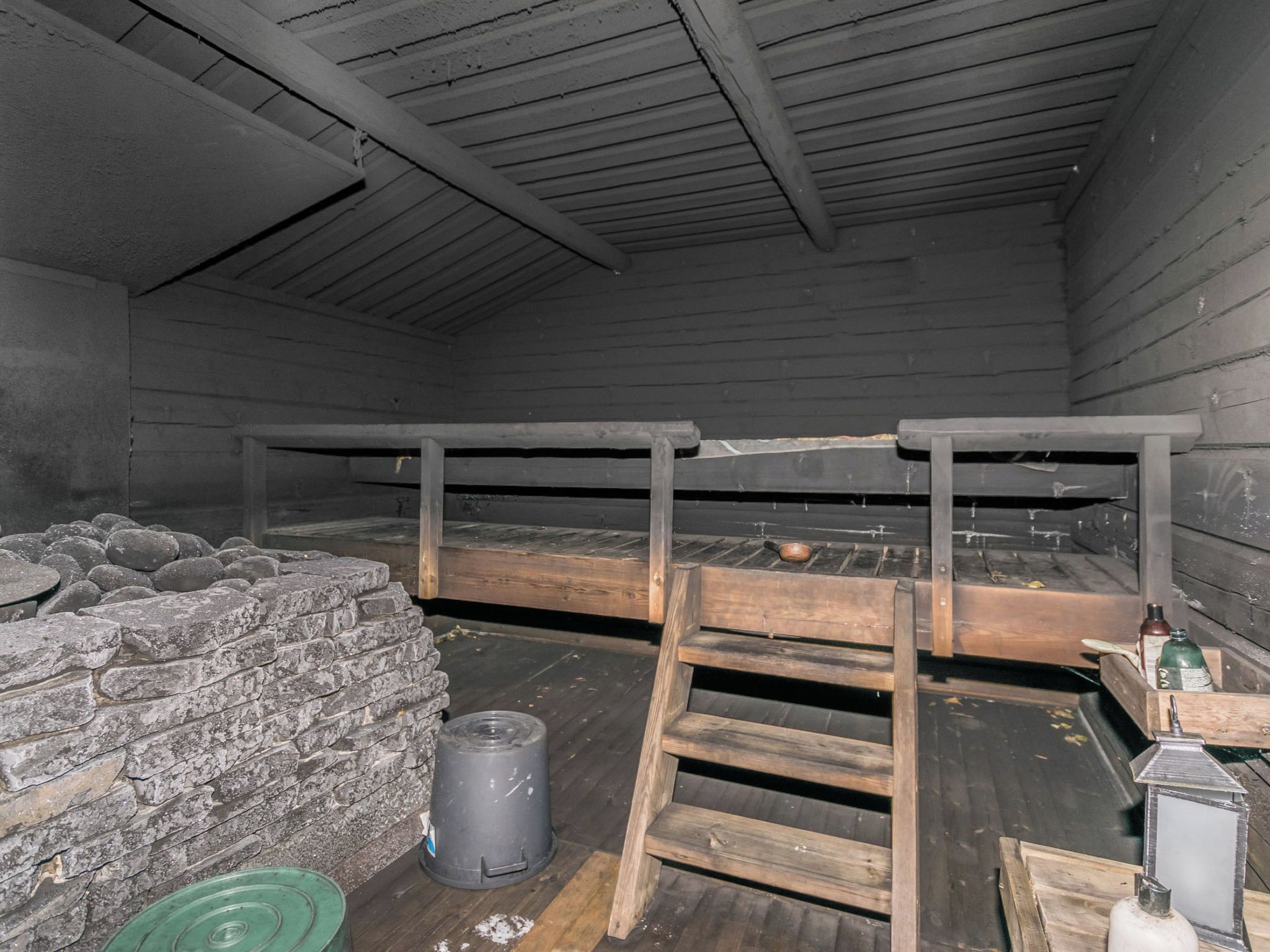 A rustic interior with a wooden bunk bed, stone wall, and a ladder.