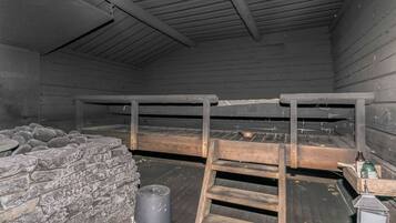 A rustic interior with a wooden bunk bed, stone wall, and a ladder.