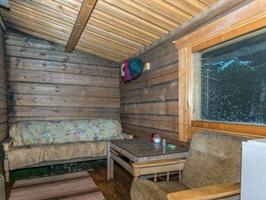 A cabin interior with a wooden bench, a small table, and a window with a view of trees. - Villa kipinä by Interhome (Viitasaari)