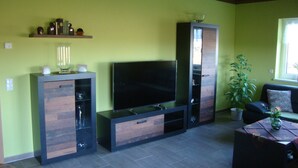 Un salon équipé d’un téléviseur à écran plat, de meubles en bois, d’une table basse et d’une plante en pot.