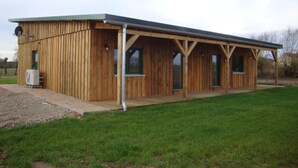 Un bâtiment en bois doté d’un patio couvert, d’une porte et de fenêtres.