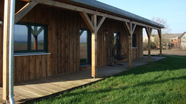 Un bâtiment en bois doté d’un porche abrité, de grandes fenêtres et d’une chaise suspendue.