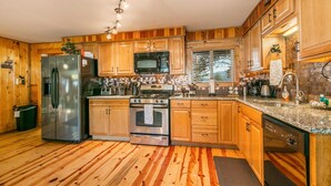 Eine Küche mit Holzausstattung, Edelstahlgeräten und einer gefliesten Spritzschutzwand.