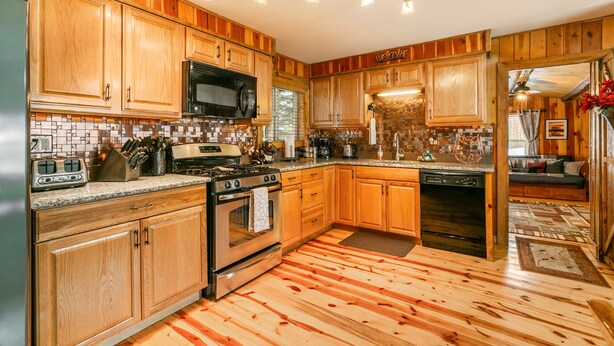 Una cocina con armarios de madera, estufa, microondas y lavavajillas.