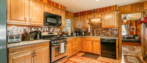 Una cocina con armarios de madera, estufa, microondas y lavavajillas.