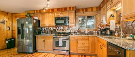 Una cocina con armarios de madera, electrodomésticos de acero inoxidable y un revoque de azulejos.