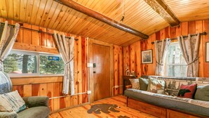 Ein Holzblockhaus-Interieur mit einer Couch, einem Sessel und einem Teppich mit Bärenmotiv.