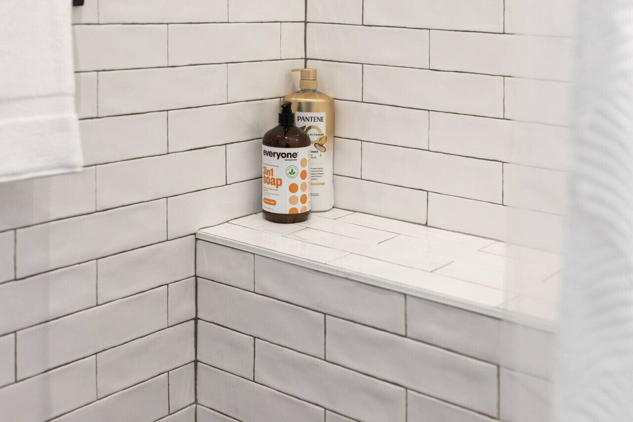 A bathroom with white tiled walls and a white countertop.