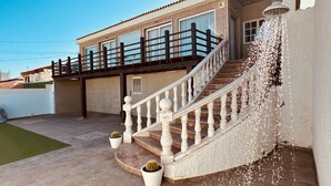 Une propriété résidentielle dotée d’un escalier menant à un balcon, d’un cactus en pot et d’un élément décoratif aquatique.