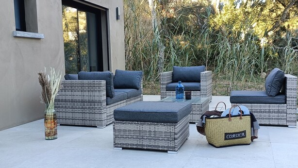 A patio with wicker furniture, including sofas and ottomans, and a wicker basket labeled "CORSICA". - Maison D'architecte 2024, Lecci Corse,15 mn de Porto-vecchio - Proche mer (Lecci)