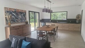 A modern kitchen with a dining area, large windows, and a contemporary art piece. - Maison D'architecte 2024, Lecci Corse,15 mn de Porto-vecchio - Proche mer (Lecci)