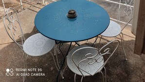 A table and chairs on a balcony with a view of a river and hills. - Maisonnette a la Campagne au Calme (Broquiès)