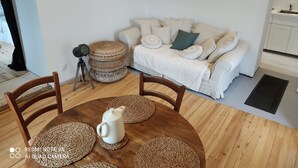 A cozy living room with a white sofa, a round coffee table, and a wooden floor. - Maisonnette a la Campagne au Calme (Broquiès)