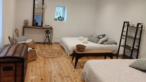A cozy room with a wooden floor, a bed with white bedding, a desk with a mirror, and a small window with a plant. - Maisonnette a la Campagne au Calme (Broquiès)