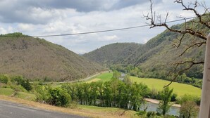 Ein Tisch und Stühle auf einem Balkon mit Blick auf einen Fluss und Hügel.