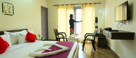 A hotel room with a bed, a desk, a chair, a TV, and a bathroom door.