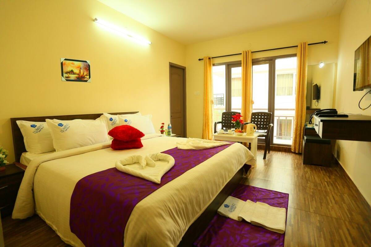 A hotel room with a bed, a desk, a chair, and a window with curtains.