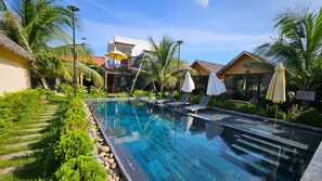 Relax by the serene pool surrounded by lush greenery and palm trees.