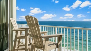 A balcony with Adirondack chairs overlooking the ocean.