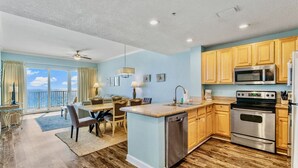 A modern kitchen with wooden cabinets, stainless steel appliances, and a dining area with a view.