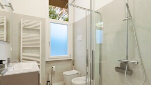 Un baño moderno con cabina de ducha de vidrio, inodoro y lavamanos.