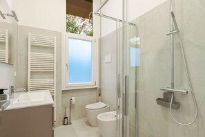 Ein modernes Badezimmer mit Duschkabine aus Glas, Toilette und Waschbecken.