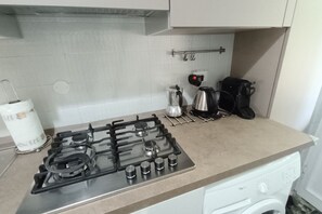 A kitchen with a gas stove, a coffee maker, and a washing machine.