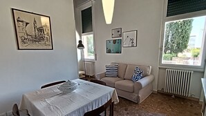 Un coin repas avec une table dressée pour deux personnes, un canapé et un radiateur.