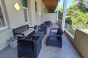 Ein Balkon mit Korbmöbeln, einer Bank und einem Blumentopf.