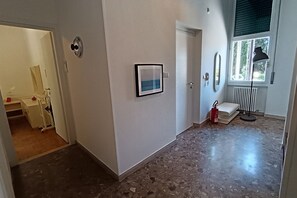 A hallway with a door, a framed picture, a radiator, and a fire extinguisher.