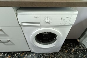 A front-loading washing machine with a control panel, a 7kg capacity label, and a front door.