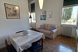 Un coin repas avec une table dressée pour deux personnes, un canapé et un radiateur.