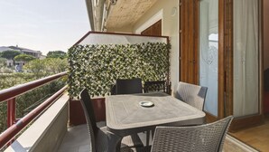 Ein Balkon mit Tisch und Stühlen, eine Holztür und Blick auf die Stadt.