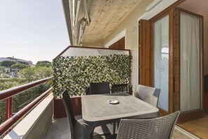 A balcony with a table and chairs, a wooden door, and a view of the city. - Azzurra Suite - studio apartment with WiFi pool and air conditioning (Sirmione)