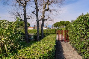 A stone pathway leading through a well-maintained garden with trimmed hedges and trees. - Suite Azzurra - Studio with Wi-Fi, Pool, and Air Conditioning (Sirmione)