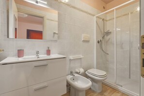 A bathroom with a shower, toilet, bidet, and a vanity with drawers and a mirror. - Azzurra Suite - studio apartment with WiFi pool and air conditioning (Sirmione)