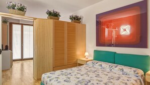 Ein Schlafzimmer mit Bett, Nachttisch, Lampe, Kleiderschrank und einem Fenster mit Blick.