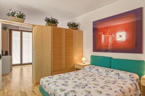 A bedroom with a bed, a nightstand, a lamp, a wardrobe, and a window with a view. - Azzurra Suite - studio apartment with WiFi pool and air conditioning (Sirmione)