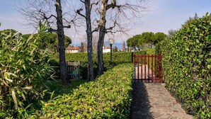 A stone pathway leading through a well-maintained garden with trimmed hedges and trees.