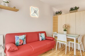 Ein modernes Wohnzimmer mit einem roten Sofa, einem Glastisch und einem Holzkabinett.