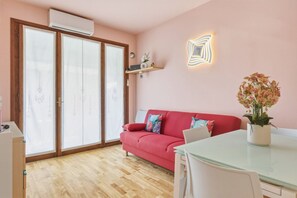 Ein Zimmer mit einem roten Sofa, einem Glastisch und einem Blumentopf.