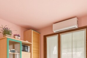 A room with a wooden cabinet, a microwave, and an air conditioning unit mounted on the wall.
