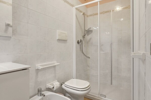 A bathroom with a toilet, a shower enclosure, and a sink.