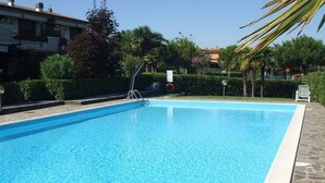 A rectangular swimming pool with clear blue water, surrounded by a stone deck.