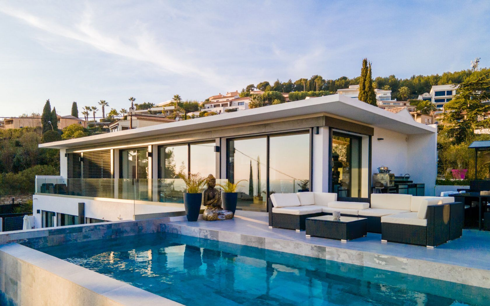 Una casa moderna con piscina, mobiliario exterior y amplias ventanas.