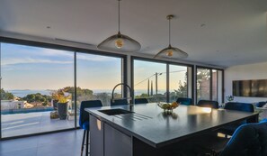 Eine moderne Küche mit einer großen Kochinsel, großen Fenstern und Blick auf die Stadt.